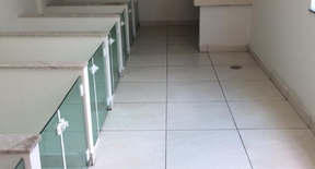 Espaço interno com piso claro e baias com divisórias de vidro